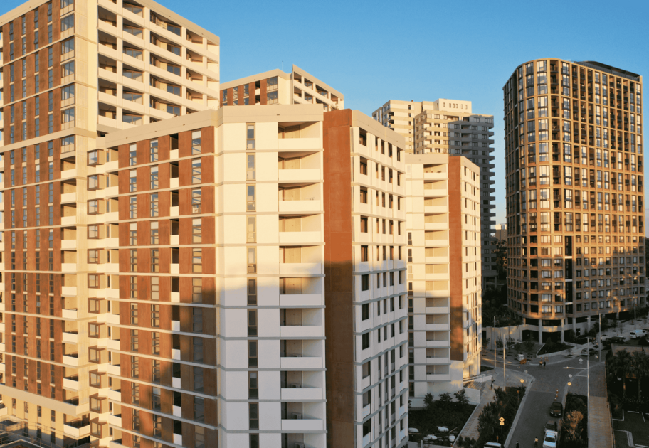 Image of MidTown Macquarie Park building set amongst a busy street, with other buildings in the background and framed by blue skies. 