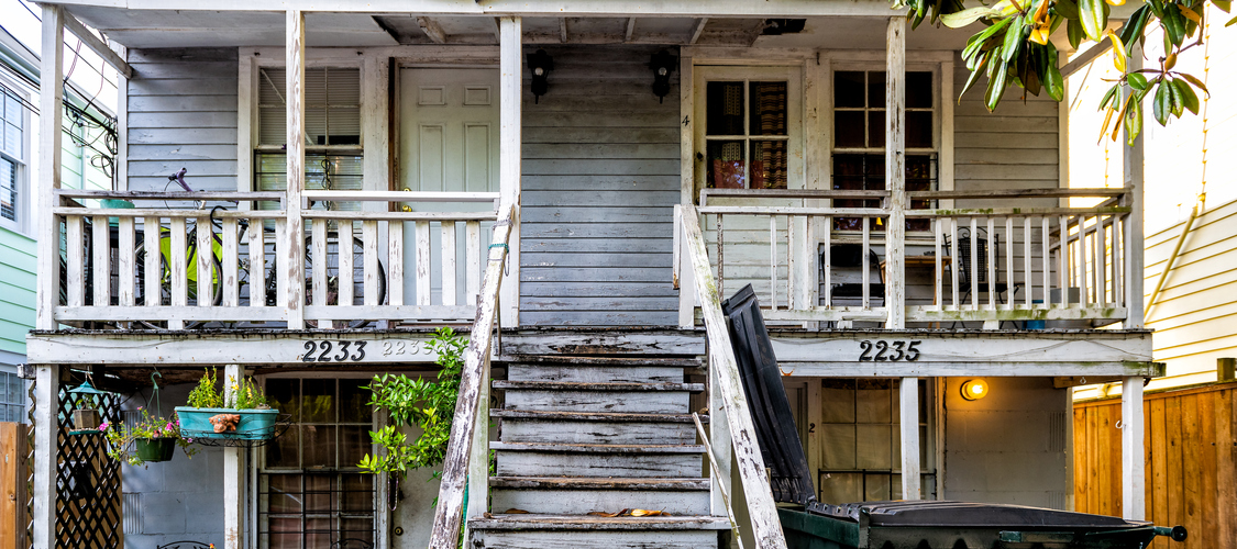 A run-down small house with a large porch.