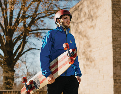 Left: Chris Holzman walks across the campus of Benedictine College in Atchison, Kan., with his longboard in hand, two years after his nearly fatal skateboarding accident. (Photo by Spirit Juice Studios)