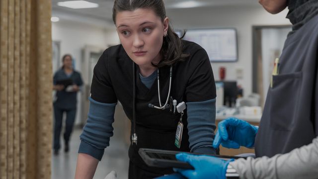 Dr. Trinity Santos leans over a patient bed, reviewing information