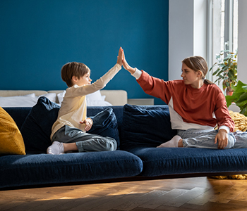 Otroka - sorojenca - sedita na kavču in si dajeta petko