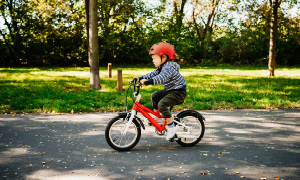 Oče uči otroka voziti kolo na mirni poti v naravi.