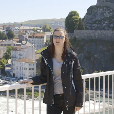 A military veteran stands on a balcony overlooking the mountainside and houses below