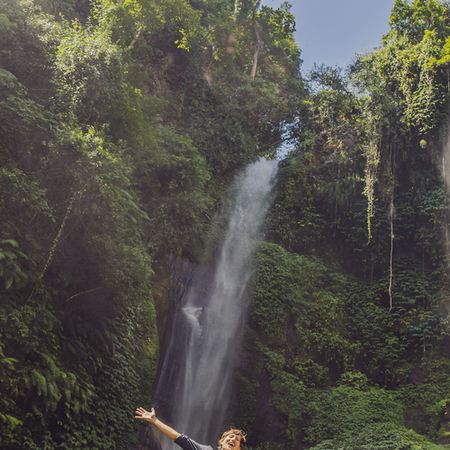 Family enjoying a beautiful waterfall. Parents and children smiling and playing in the refreshing water.