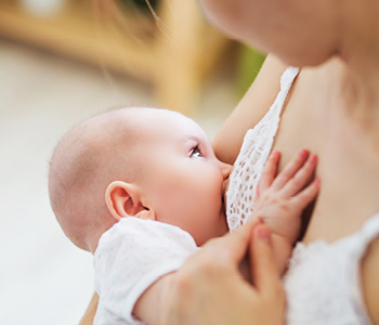 Prikupen dojenček se doji v materinem naročju, mama pa zaupa, da bo popil dovolj mleka