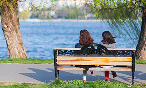 Simbolna slika za nasvet o možganski kapi in njenih posledicah - dve dekleti sedita na klopi ob jezeru na sončen spomladanski dan.