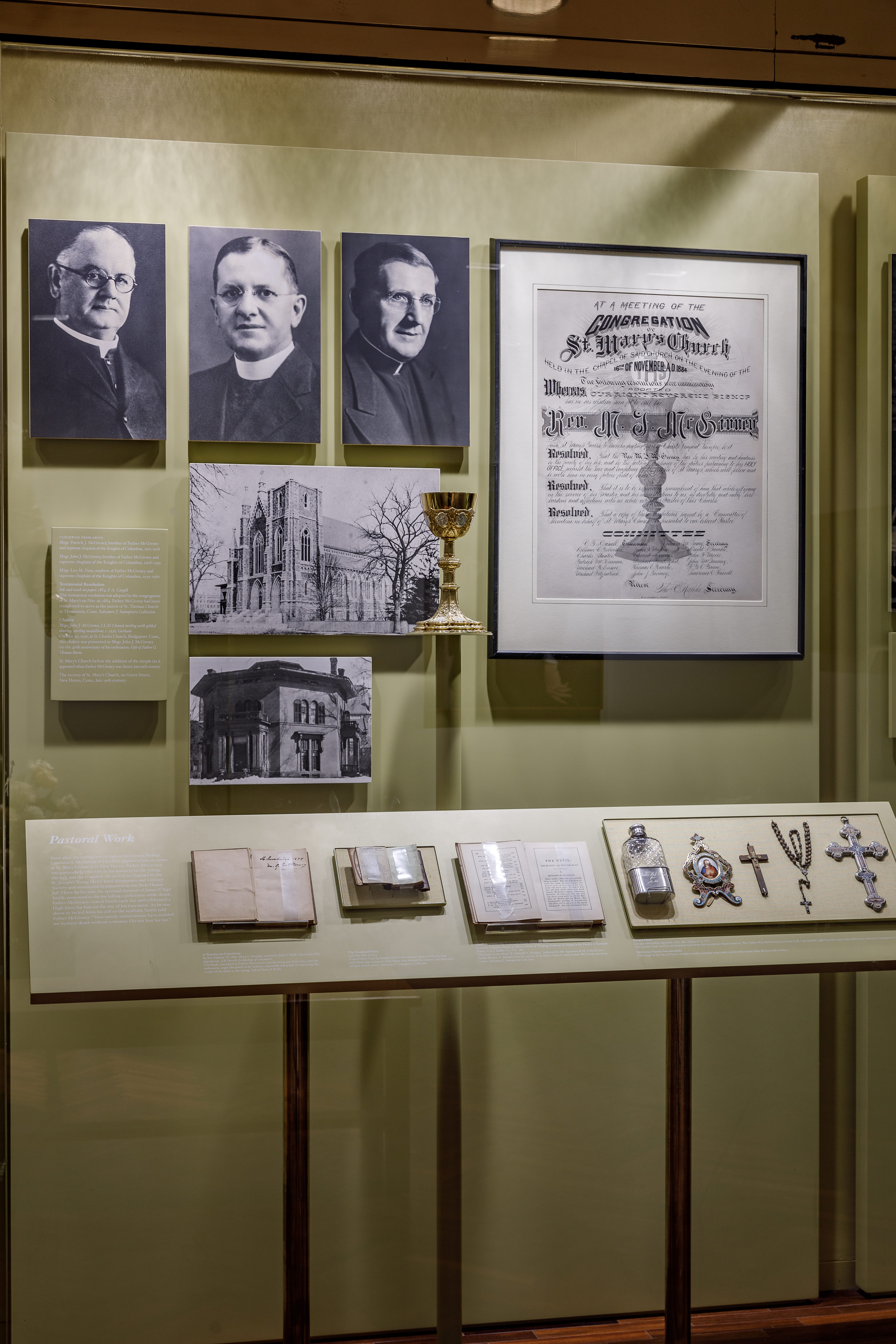 Wall case of Father Michael J. McGivney gallery discussing his pastoral work in New Haven, Connecticut. 