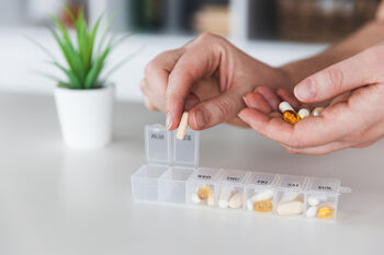 patient putting pills in medication organization container