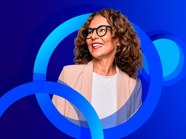 A smiling woman with curly hair and black-framed glasses, wearing a light-colored blazer over a white top, looks to the side. The image is set against a dark blue background with bright blue concentric circles.