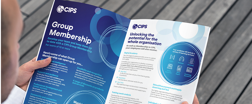 A close-up, over-the-shoulder view of a person holding and reading an open brochure titled "Group Membership" from the organization CIPS. The brochure features deep blue and white text and graphics discussing membership benefits.
