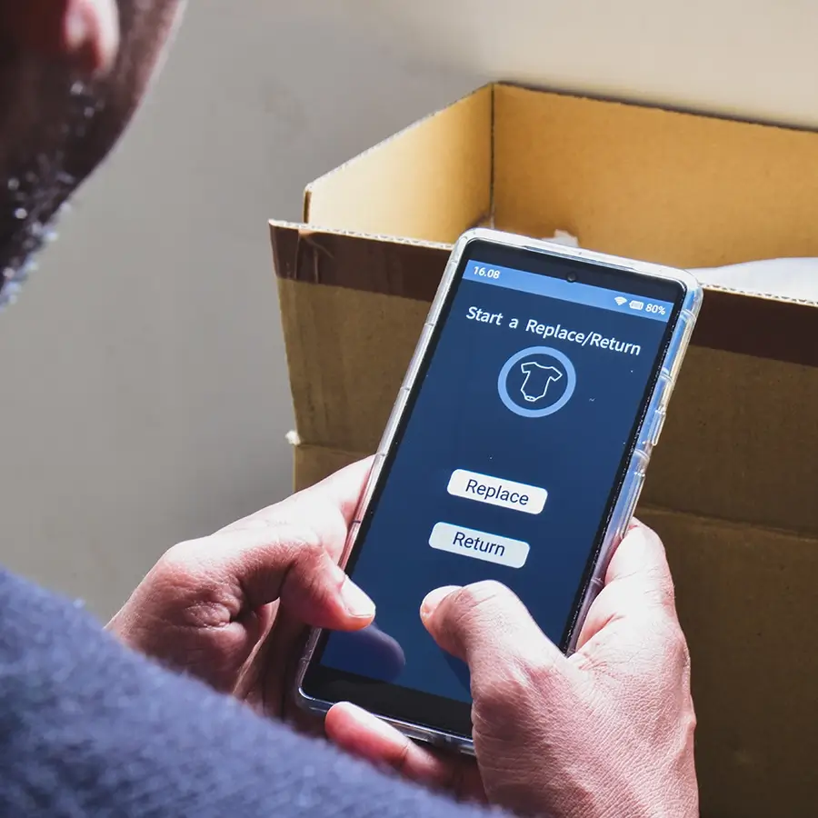 modern-om-cost-optimizer-improve-efficiency-900x900.webp Close-up of a person holding a smartphone and selecting a “Replace” or “Return” option on a retail app, with an open cardboard box in the background, illustrating an online product return process.