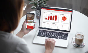 Ženska na računalniku in telefonu z Moj GENERALI pregleduje svoje zavarovalne police.