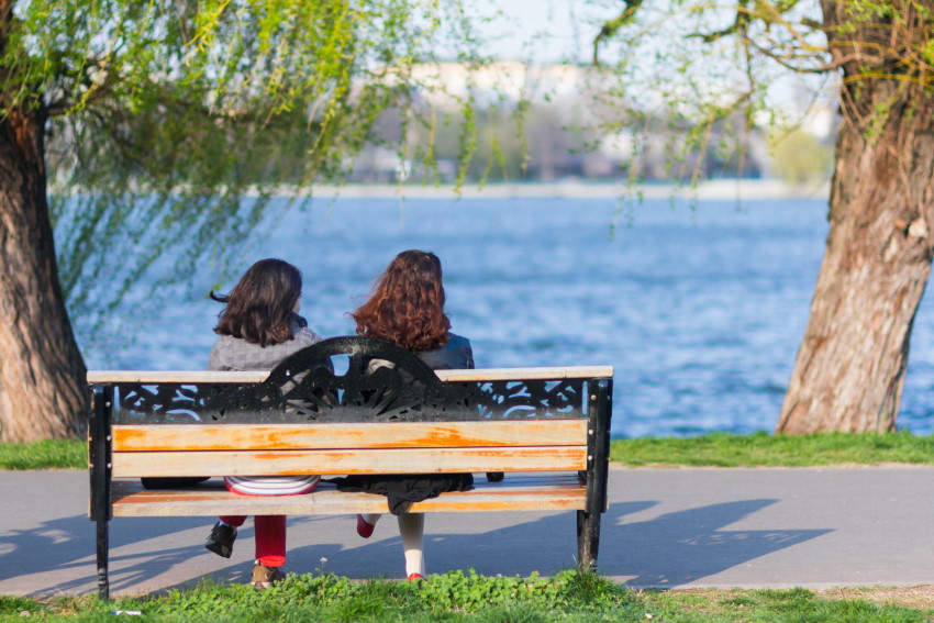 Simbolna slika za nasvet o možganski kapi in njenih posledicah - dve dekleti sedita na klopi ob jezeru na sončen spomladanski dan.