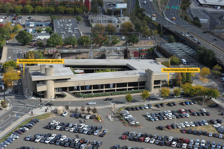 Aerial photo of the McGivney Pilgrimage Center enhanced to indicate in Spanish the bus and van parking along with the free parking beneath the building. 