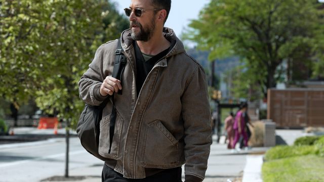 Dr. Michael “Robby” Robinavitch walks outdoors with a shoulder bag, wearing a jacket and sunglasses.