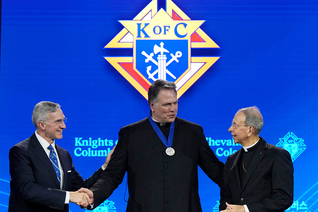 Supreme Knight Patrick Kelly and Supreme Chaplain Archbishop William Lori congratulate Father Chad Wilhelm at the awards session prior to the 142nd Supreme Convention in Québec City on Aug. 5. (Photo by Paul Haring)
