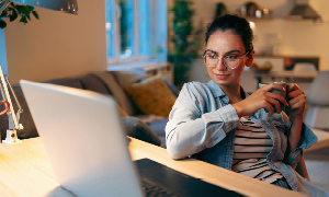 Mlada ženska sedi za računalnikom in načrtuje korak za grajenje svoje osebne blagovne znamke.