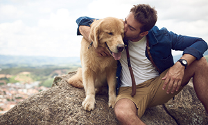 Pes z lastnikom počiva na skali - simbolna slika za pohodništvo s psom