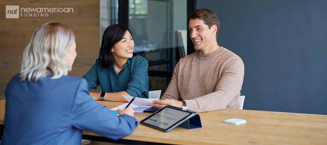 A couple sitting across a desk from a loan officer.