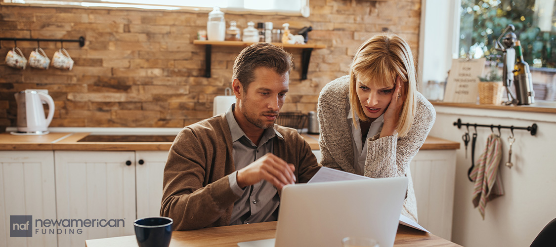A couple looking worriedly at a a laptop.