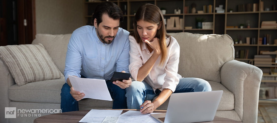 A couple looking at paperwork while sitting on a couch.