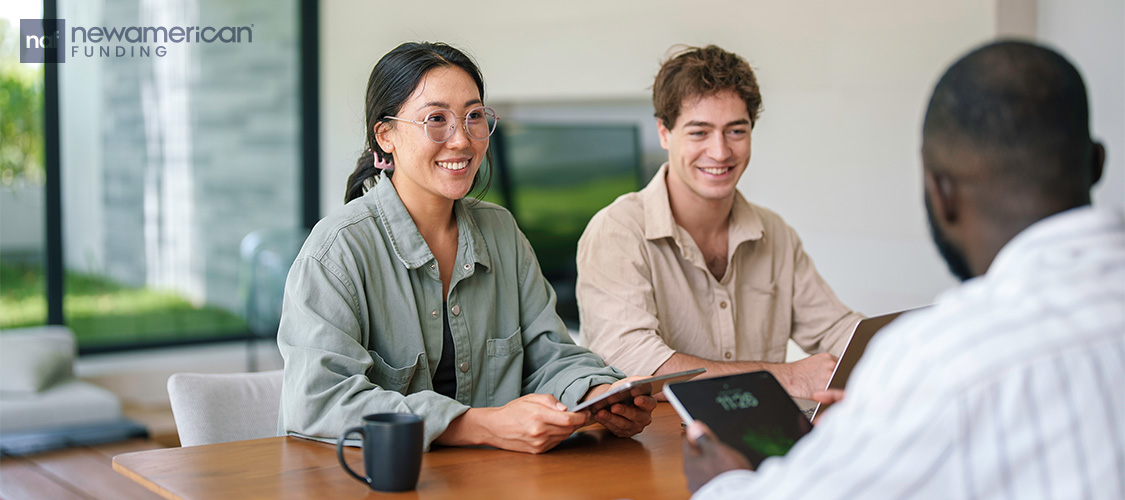 A couple sitting at a desk across from a loan officer.