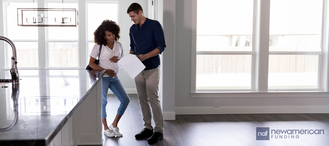 A couple looking at paperwork in an empty house.