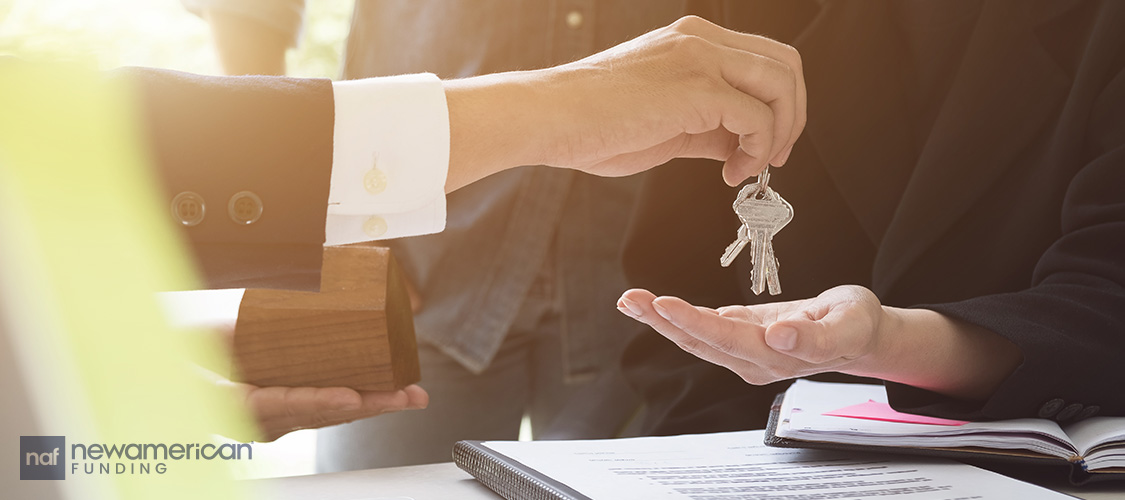 A hand dropping keys into another hand.