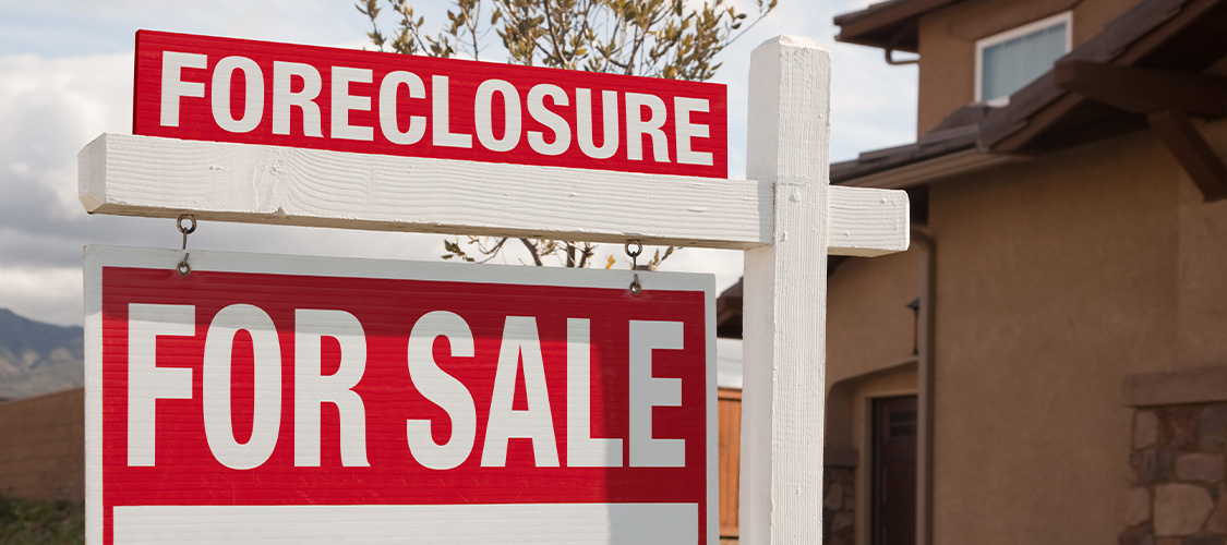 A for sale sign with foreclosure on top of it