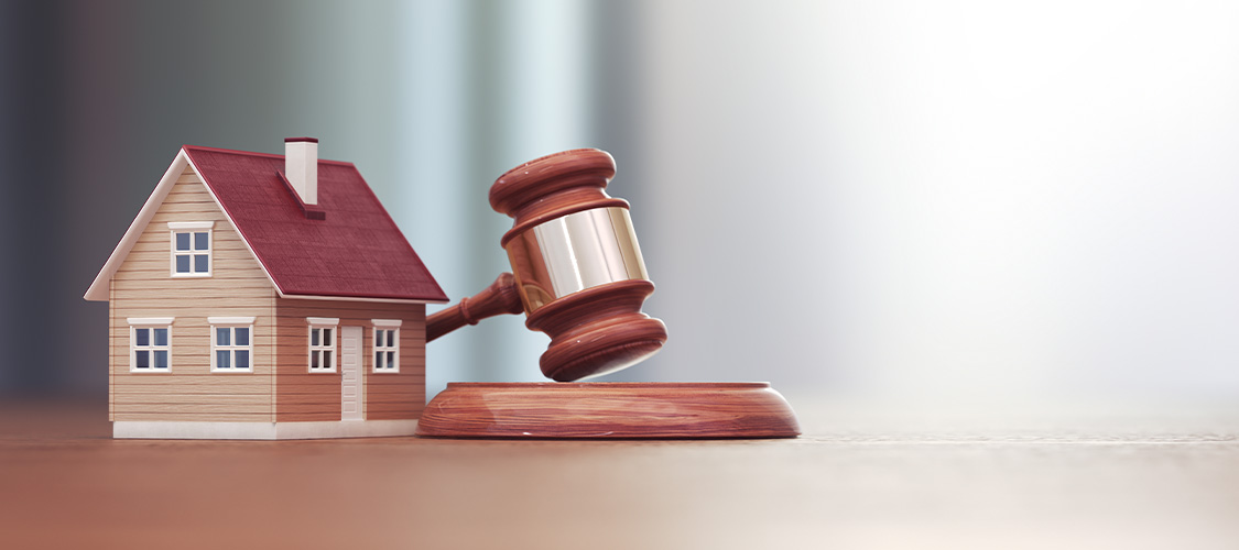 A small model of a home with a gavel next to it