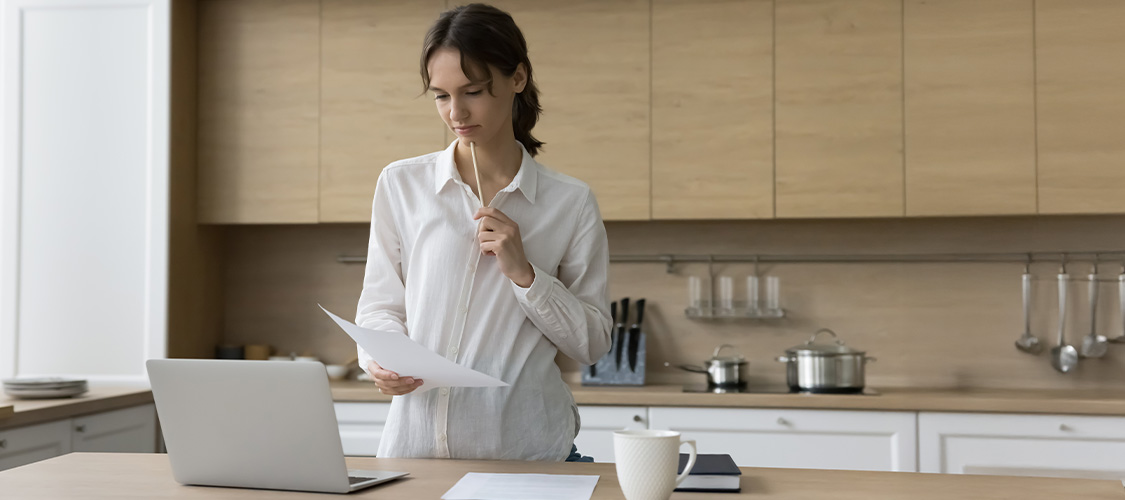 A woman standing in her kitchen making a decision