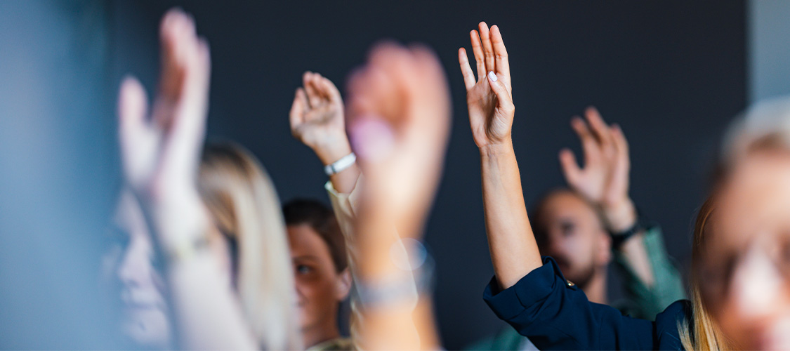 People raising their hands in a classroom