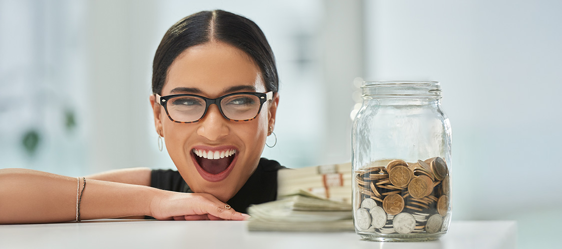 A woman smiling at a jar full of change