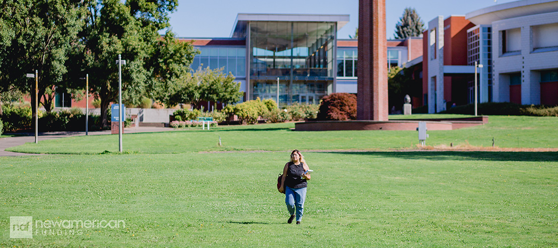 A college student walking across a lawn.