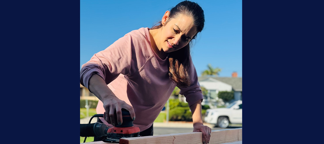 Jenna Luchau&nbsp;working on a piece of wood outside.
