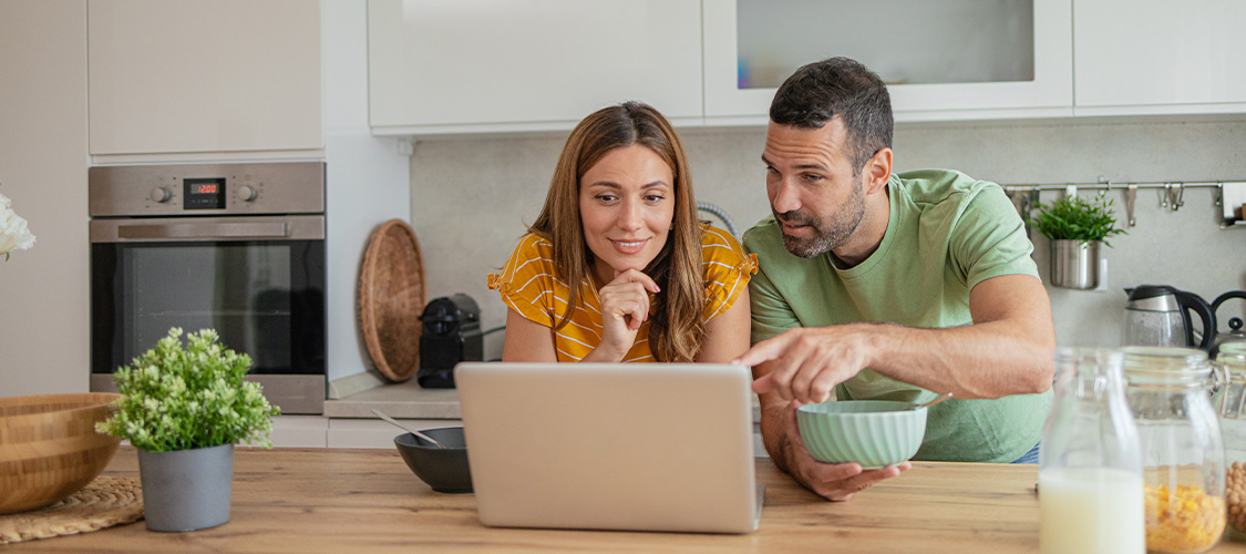 A couple using a computer in their kitchen