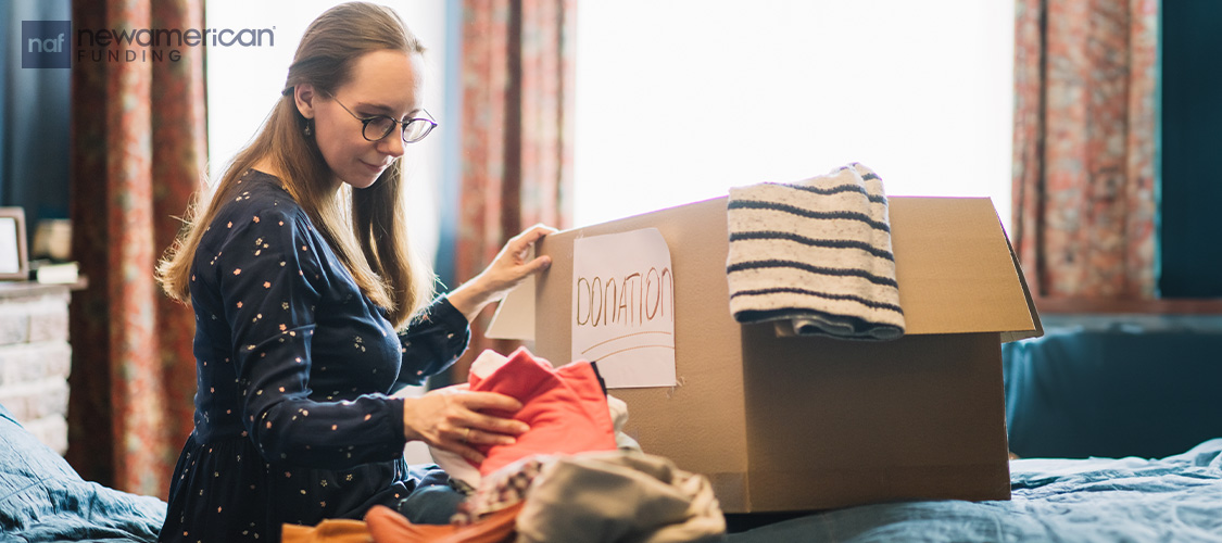 A woman sorting through belongings and putting them into a box.