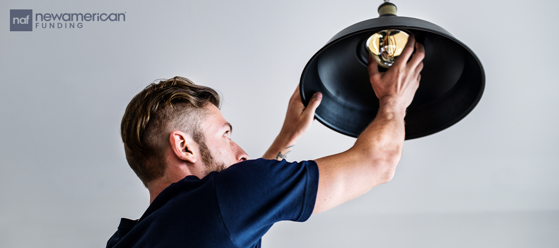 A man changing a ceiling light fixture.