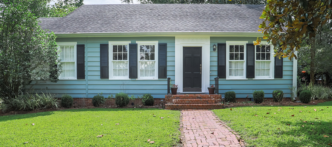A blue house with shutters on the windows