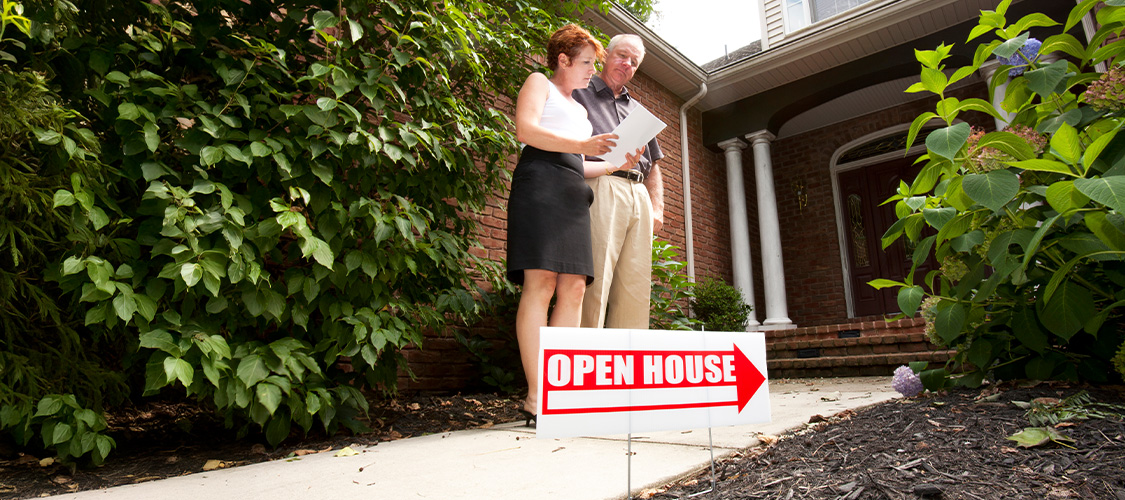 A man and woman standing outside of an open house