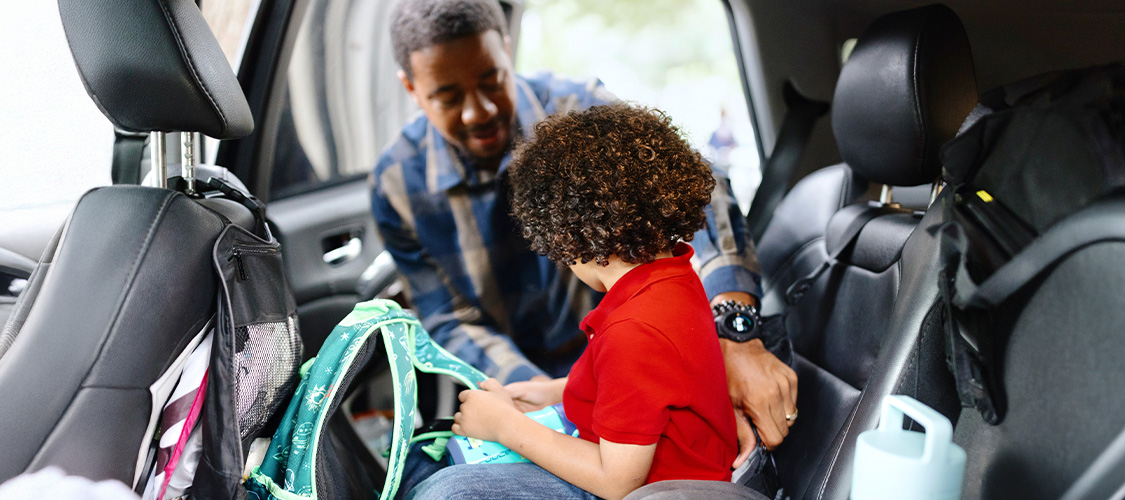 A father putting his son in a car seat