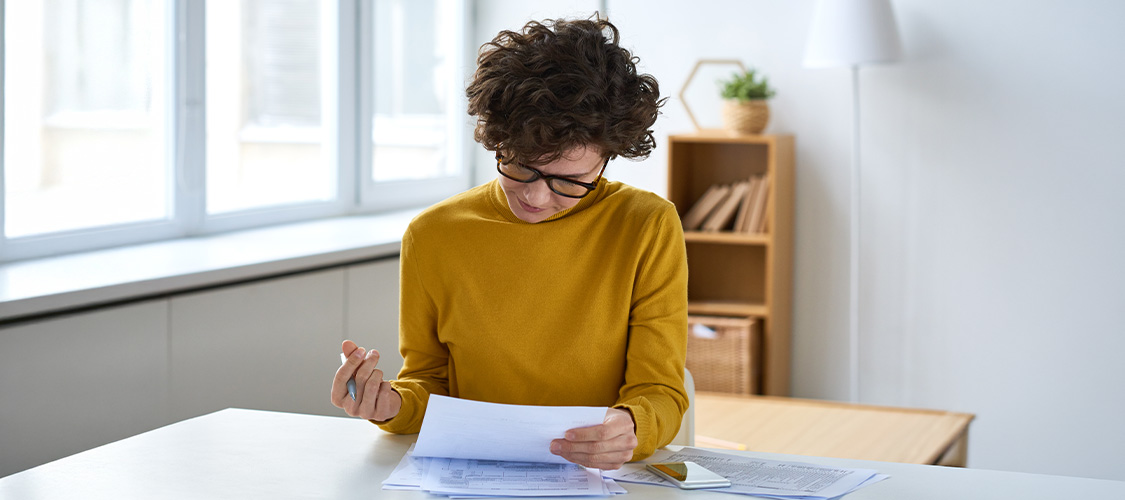 A woman sitting at a desk looking at paperwork.