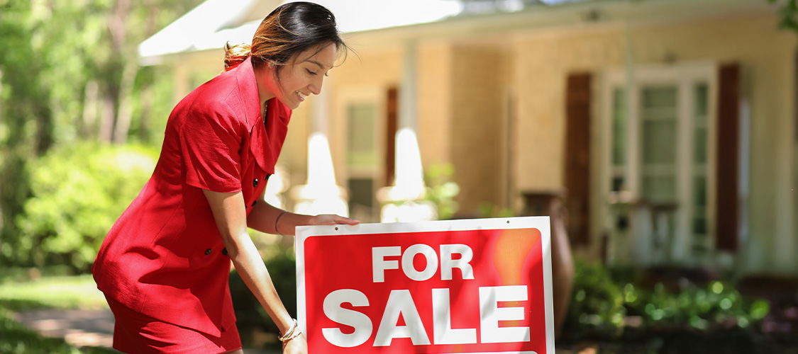 someone planting a for sale sign in front of their home
