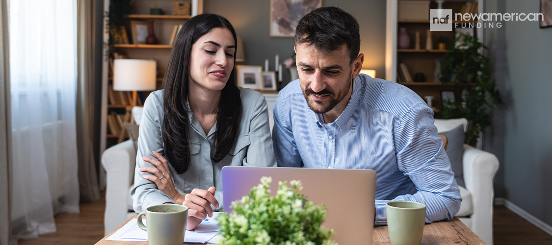 A couple sitting in front of a laptop.