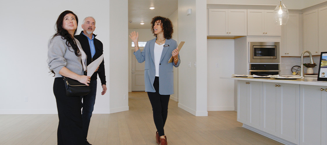 A couple touring a home with a real estate agent showing them the kitchen.
