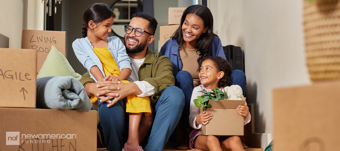 A family with two young kids surrounded by moving boxes.