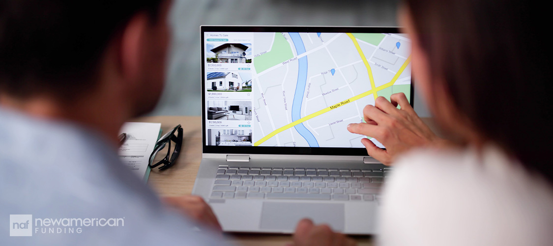 A couple at a computer pointing at a home listing