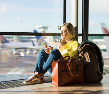 Mlado dekle se med čakanjem na potovanje z letalom zabava na telefonu.