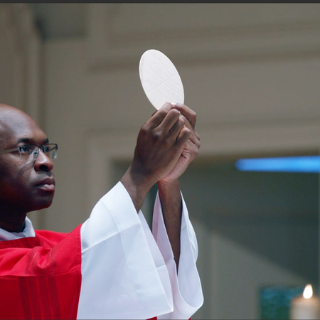 Priest raising the eucharist at church, kofc helps fund the education of seminarians preparing to become Catholic chaplains in the U.S.