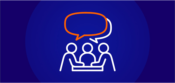 A white line-art icon on a dark blue background showing three people seated around a table, with an orange and white speech bubble floating above them, symbolizing applied learning or group discussion.